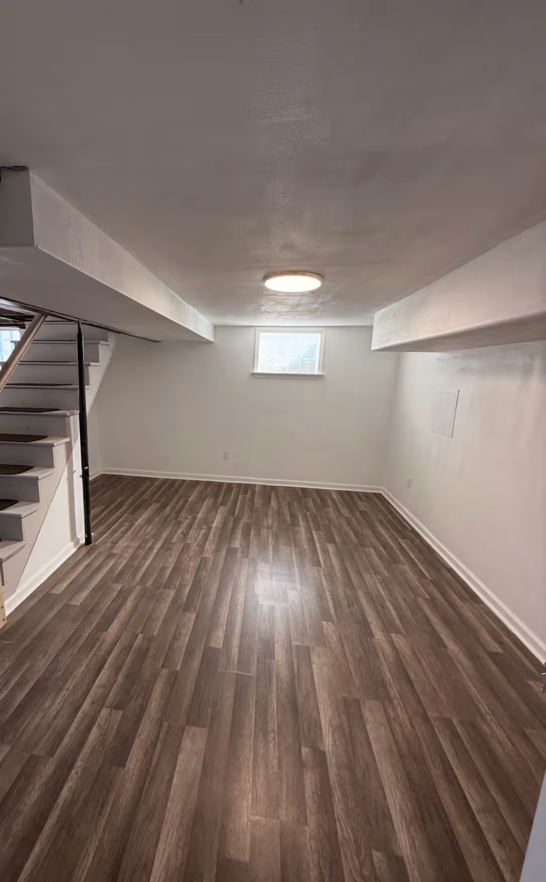 Finished basement room with new flooring and white walls