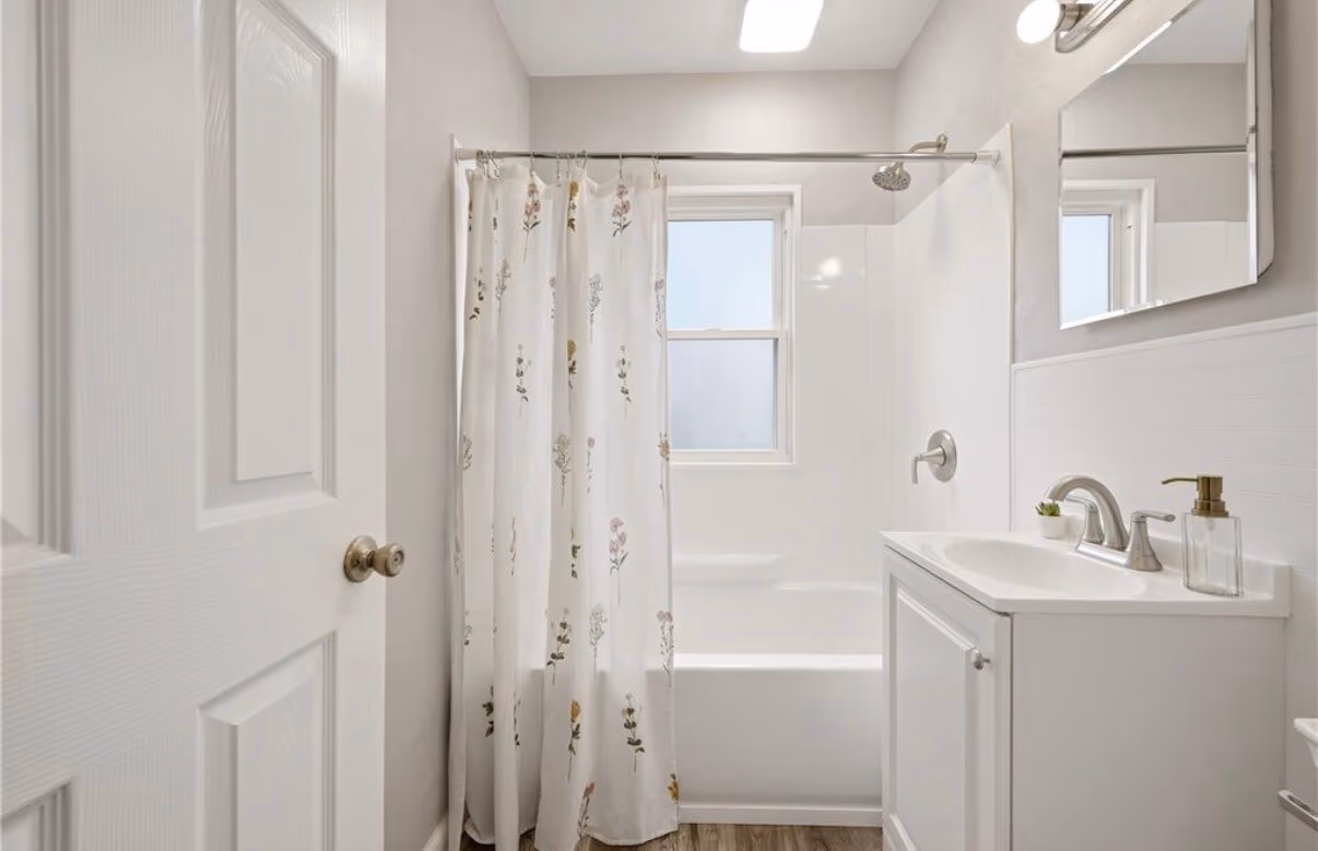 Finished compact bathroom with shower, pedestal sink, toilet, and built-in storage