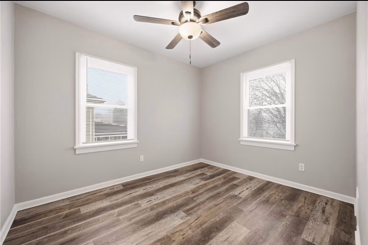 Finished bedroom with new flooring, fresh paint, and two windows