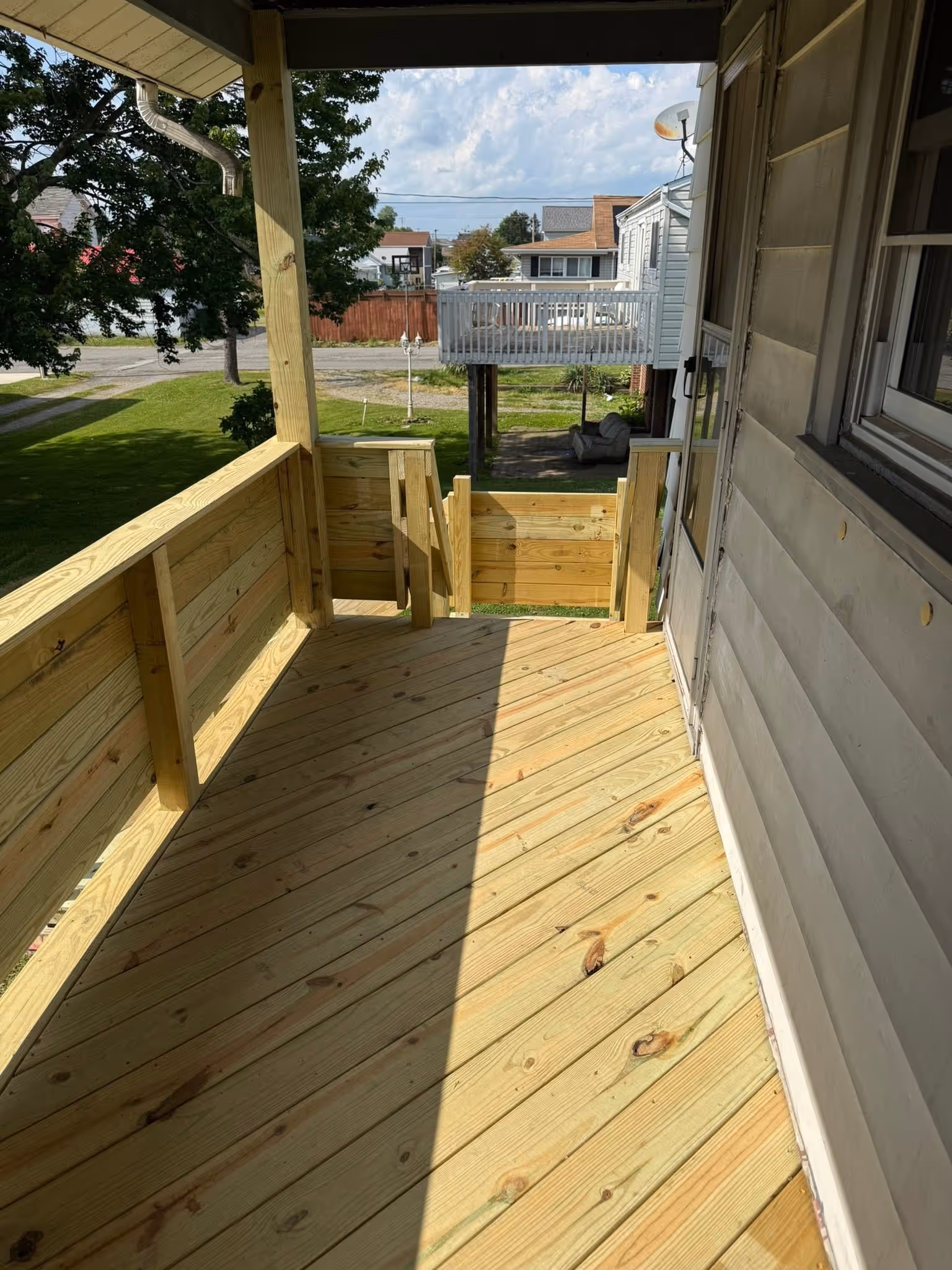 New wood deck and railing beside a home