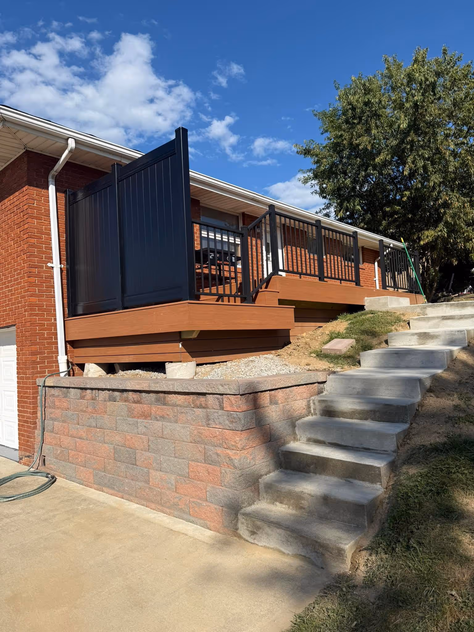 Finished deck with privacy panel above a retaining wall and concrete stairs