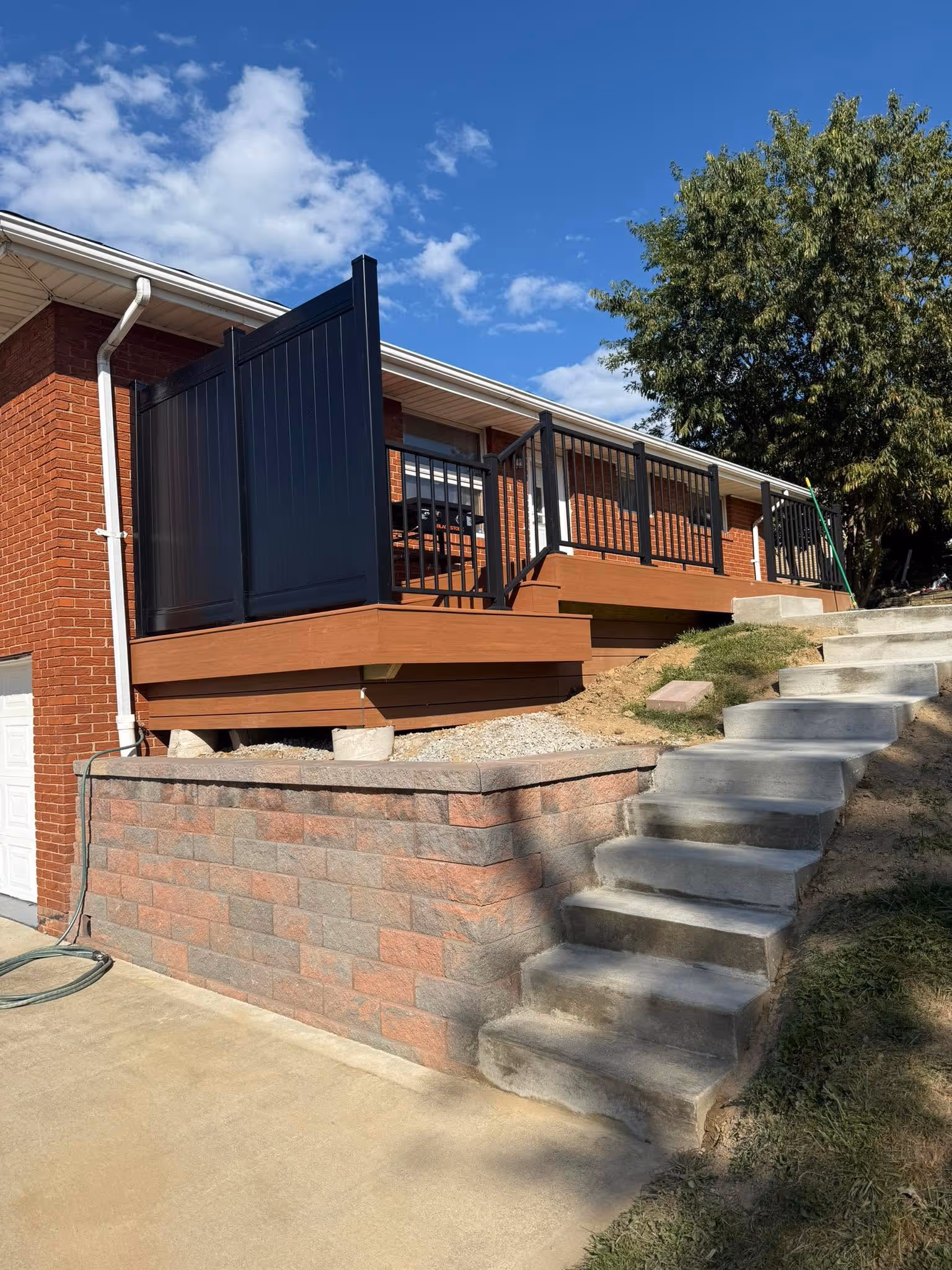 Deck with a privacy panel above a retaining wall and concrete stairs