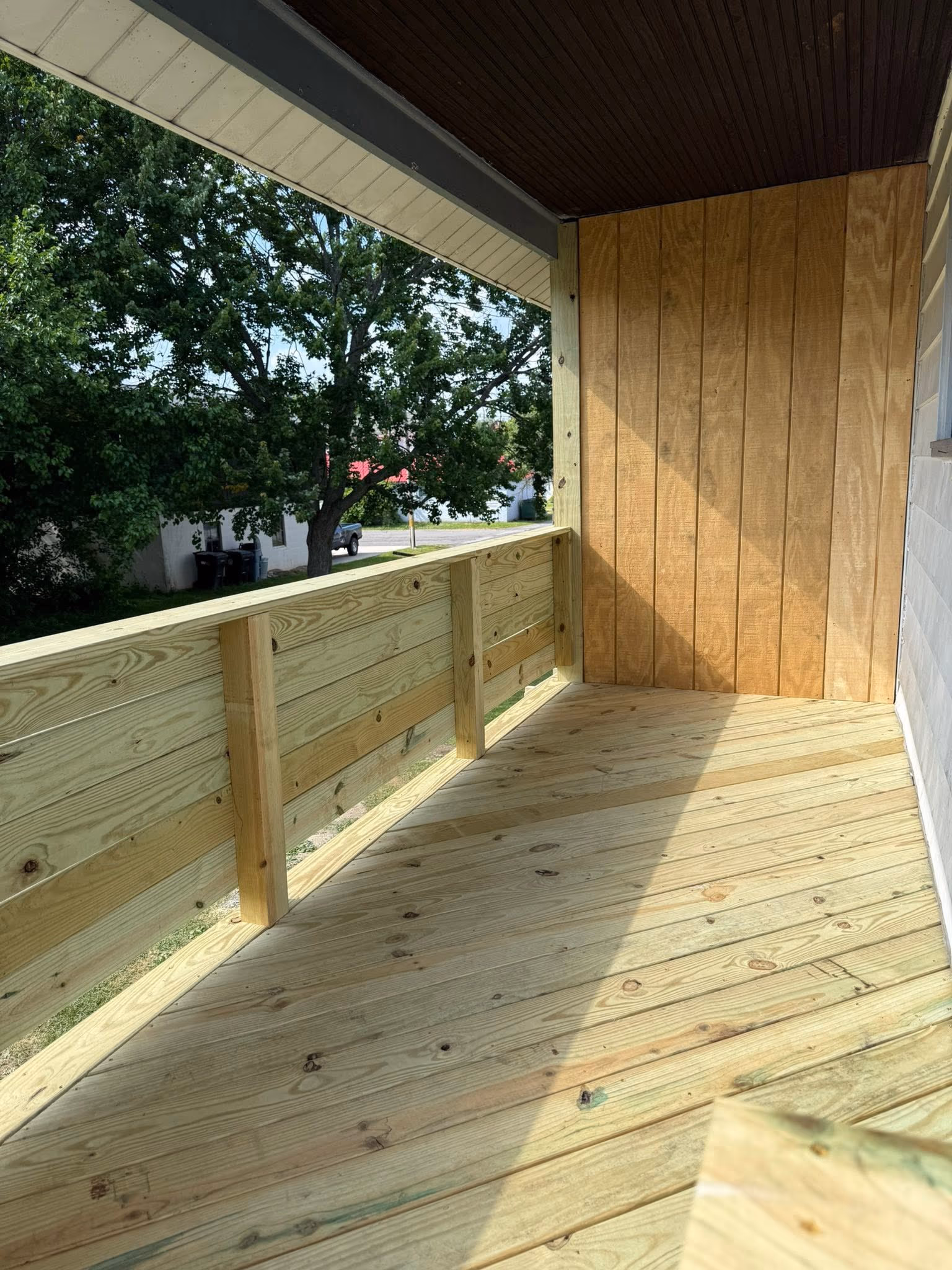 Covered wood porch corner with railing and finished ceiling